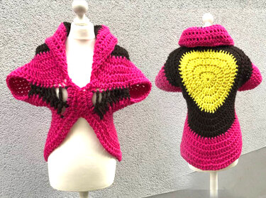 Gehäkelter kurzärmeliger Seelenwärmer in Pink mit schwarzen Einsätzen und rundem gelbem Rückenmotiv auf Schaufensterpuppe