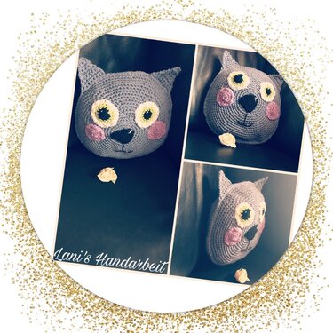 Runde graue Häkel-Kissenhülle mit appliziertem Katzengesicht und angenähten Ohren