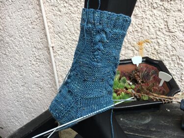 Blaue gestrickte Damensocke mit Zopf- und Lochmuster auf Sockenform, Ferse am Nadelspiel