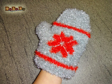 Hand mit gehäkeltem silbergrauen Waschhandschuh mit roten Streifen und Stern