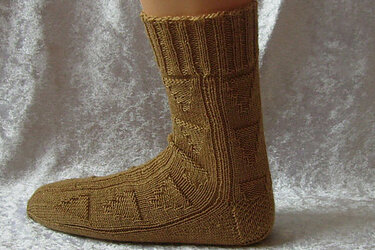 Ockerfarbene gestrickte Socke mit geometrischem Strukturmuster an einem Fuß