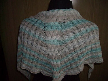 Halbrundes gestricktes Tuch auf dunklem Büstenmodell, cremeweiß mit türkisen und sandfarbenen Streifen, Ajourmuster und gewelltem Rand