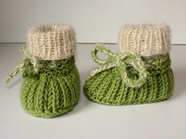 Gestrickte grüne Babyschuhe mit Umschlag und Bindekordel, Nahaufnahme