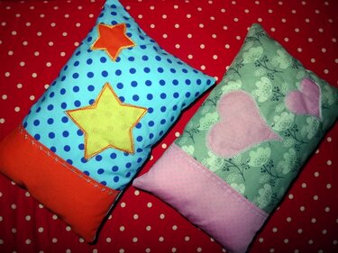 Zwei rechteckige Kissen mit Kontrastborten und applizierten Sternen und Herzen