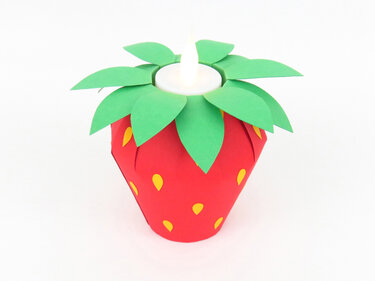 Rote Papier-Erdbeer-Laterne mit grünen Blättern und gelben Samen, oben ein leuchtendes LED-Teelicht