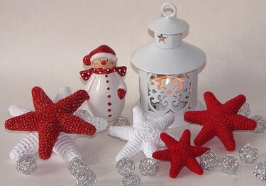 Rot-weiße gehäkelte 3D-Sterne als Weihnachtsdeko neben Laterne und Schneemannfigur