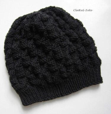 Schwarze Strickmütze mit diagonalem Rautenmuster und geripptem Bund auf weißem Hintergrund