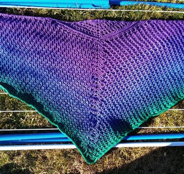 Gehäkeltes Dreieckstuch mit Farbverlauf Lila zu Türkisgrün auf Wäscheständer im Gras