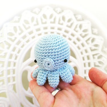 Hellblauer gehäkelter Amigurumi-Oktopus in einer Hand