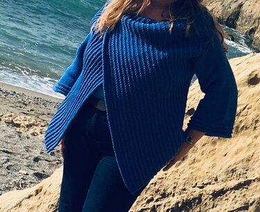 Person am Strand mit maritimem blauem Strickcardigan und breitem Schalkragen