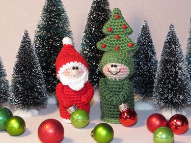 Zwei gehäkelte Figuren (Nikolaus und Tanne) vor Mini-Tannenbäumen und roten sowie grünen Christbaumkugeln