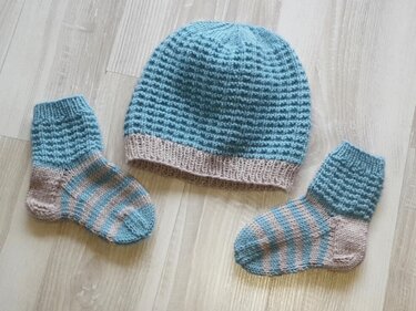 Pastellblaue gestrickte Mütze mit Waffelmuster und zwei gestreiften Babysocken