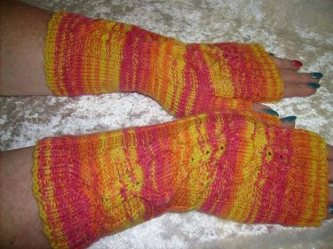 Gemusterte, fingerlose Armstulpen in Gelb, Pink und Orange, getragen an Unterarmen