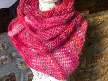 Gestricktes dreieckiges Tuch in verschiedenen Pinktönen mit offener, flauschiger Struktur auf einer Schneiderpuppe drapiert