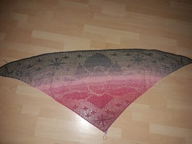 Gehäkeltes Dreieckstuch in Grau und Rosa mit offenem Lochmuster auf hellem Boden