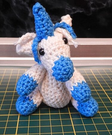 Gehäkeltes blau-weißes Amigurumi-Einhorn mit Horn und schwarzen Augen