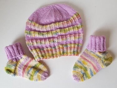 Gestrickte Babymütze mit Rippenbündchen und zwei gestreiften Babysöckchen
