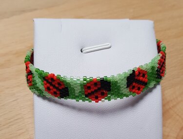 Handgefädeltes grünes Perlenarmband mit roten Marienkäfern