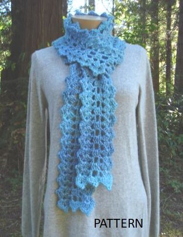 Mannequin wearing a light-blue crocheted lace scarf with scalloped ends