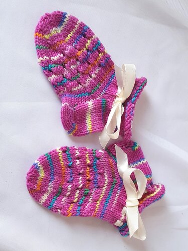 Gestricktes Paar Babysöckchen in Pink mit mehrfarbigen Streifen und weißer Schleife