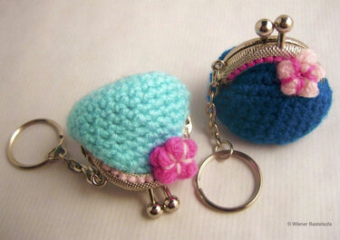 Zwei gehäkelte runde Münztäschchen als Schlüsselanhänger, helltürkis und dunkelblau, mit Metallbügel und rosa Blüten