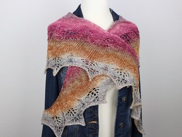 Gestricktes halbrundes Tuch in Pink-Orange-Grau mit dekorativer Lochspitze über Jeansjacke