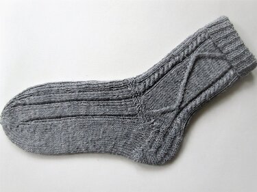 Gestrickte graue Herrensocke mit Zopfmuster und Rippenbündchen, seitliche Ansicht auf weißem Hintergrund