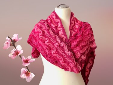 Fein gestricktes Dreieckstuch in Rosa-Magenta mit Ajour- und Wellenmuster auf einer Schaufensterpuppe