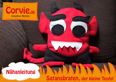 Rotes Teufelkissen aus Stoff mit applizierten Augen, gezackten Zähnen, Hörnern und Schwanz auf einem Sofa
