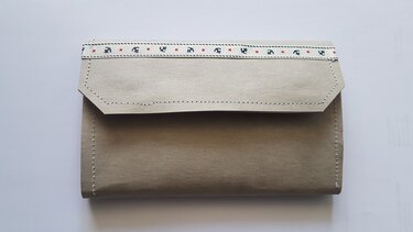 Beiges Umschlag-Portemonnaie aus Stoff mit sichtbaren Nähten und dekorativem Webband