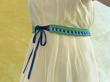 Gehäkelter grüner und blauer Taillengürtel mit blauem Satinband an cremefarbenem Kleid