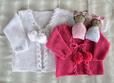 Zwei gestrickte Babyjacken (weiß, fuchsia) mit Zopfmuster und Bommeln