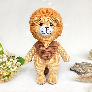 Gehäkelter Amigurumi-Löwe in Beige mit orangefarbener Mähne und braunem Halstuch