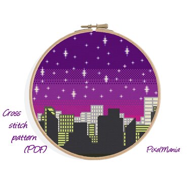 Stickrahmen mit Kreuzstich-Motiv: dunkle Stadtsilhouette vor lila-violettem Sternenhimmel