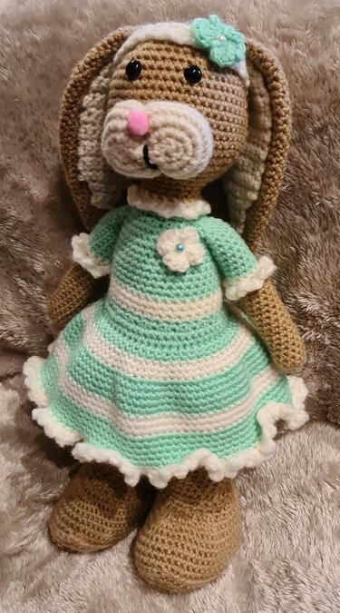 Gehäkelter brauner Hase mit mint-creme gestreiftem Kleid und Blumen