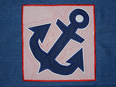 Quadratisches gesticktes Anker-Applikationsmotiv in Dunkelblau mit roten Fülllinien und rotem Rand auf jeansblauem Stoff