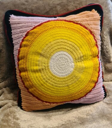 Quadratischer gehäkelter Kissenbezug mit gelber Rundapplikation und rosa Rippenstruktur