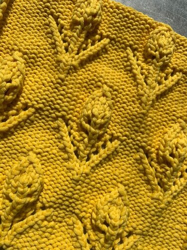 Gelbes Strickstück mit wiederkehrendem, dreidimensionalem Blattmuster