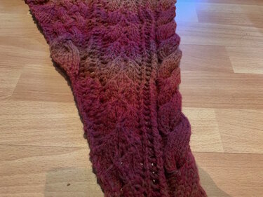 Gestricktes Dreieckstuch mit Zopfmuster und Rot-Braun-Farbverlauf auf Holzboden