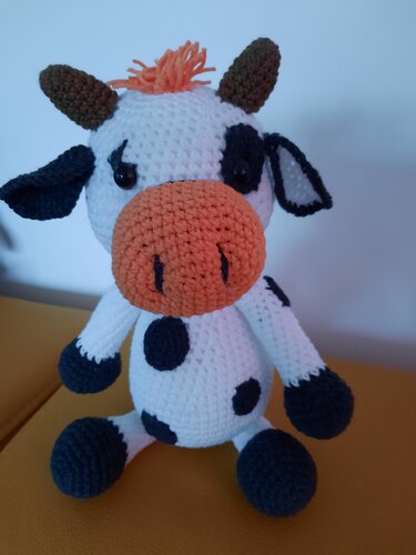 Gehäkelte Amigurumi-Kuh mit weißen, schwarzen und orangen Details