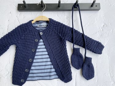 Marineblaue gestrickte Babyjacke mit Fäustlingen an Schnur, daneben gestreiftes Shirt