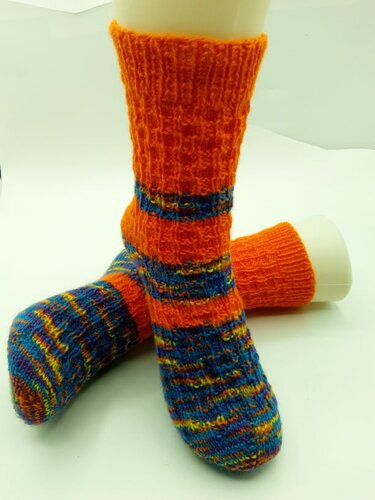 Gestrickte orange-bunte Socken auf hellem Untergrund