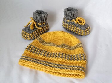 Gestrickte Babymütze in Gelb-Grau mit Streifen und Strukturmuster sowie zwei passende Babyschühchen mit Bindebändern