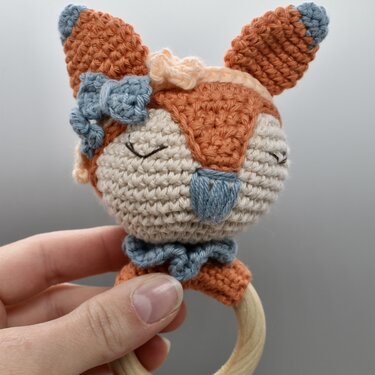 Gehäkelte Fuchs-Rassel mit Holzring, Nahaufnahme in Hand