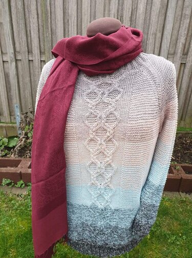 Raglanpullover mit mittiger Zopfmusterbahn und krausrechter Textur auf Schneiderpuppe