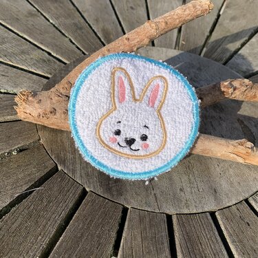 Runde gestickte Applikation mit Hasengesicht, weißer Oberfläche und hellblauem Rand