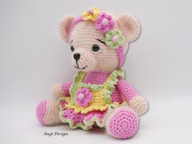 Gehäkelter Amigurumi-Teddybär in rosa Kleid mit Rüschen und Blumenstirnband