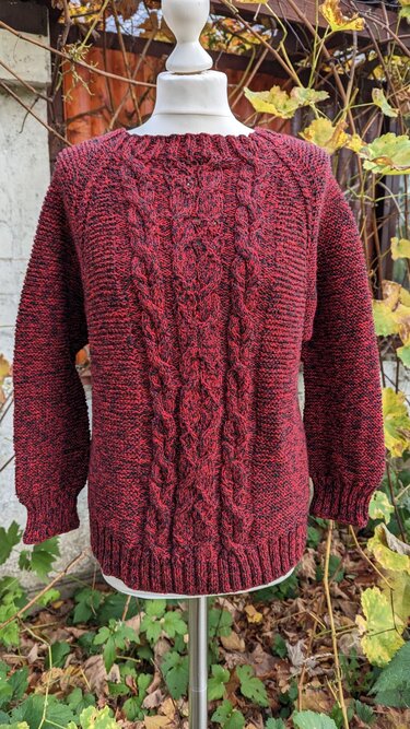 Dunkelroter gestrickter Damenpullover mit mittigem Zopfmuster auf Schaufensterpuppe