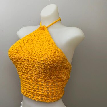 Yellow crochet halter top with textured bodice and openwork midriff on a white mannequin