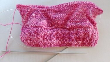 Rosa Strickschal in Arbeit auf Rundstricknadel mit strukturiertem Muster